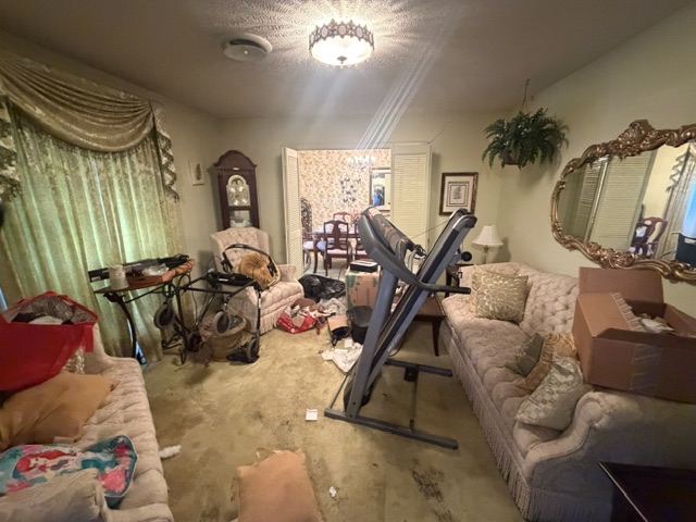 Cluttered living room full of furniture and belongings before cleanout