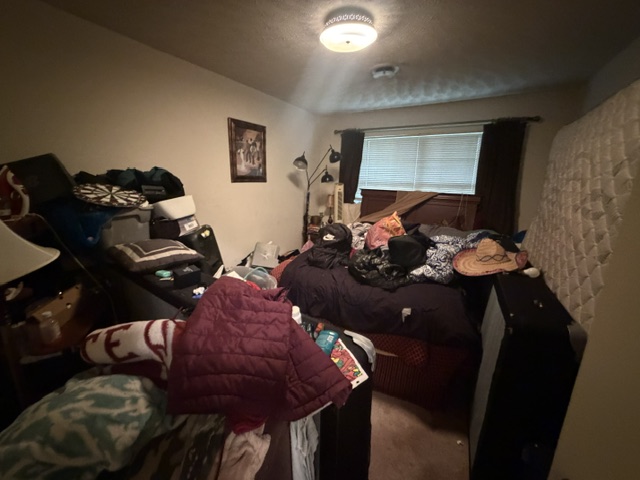 Messy bedroom with clutter on the bed and floor before cleanout